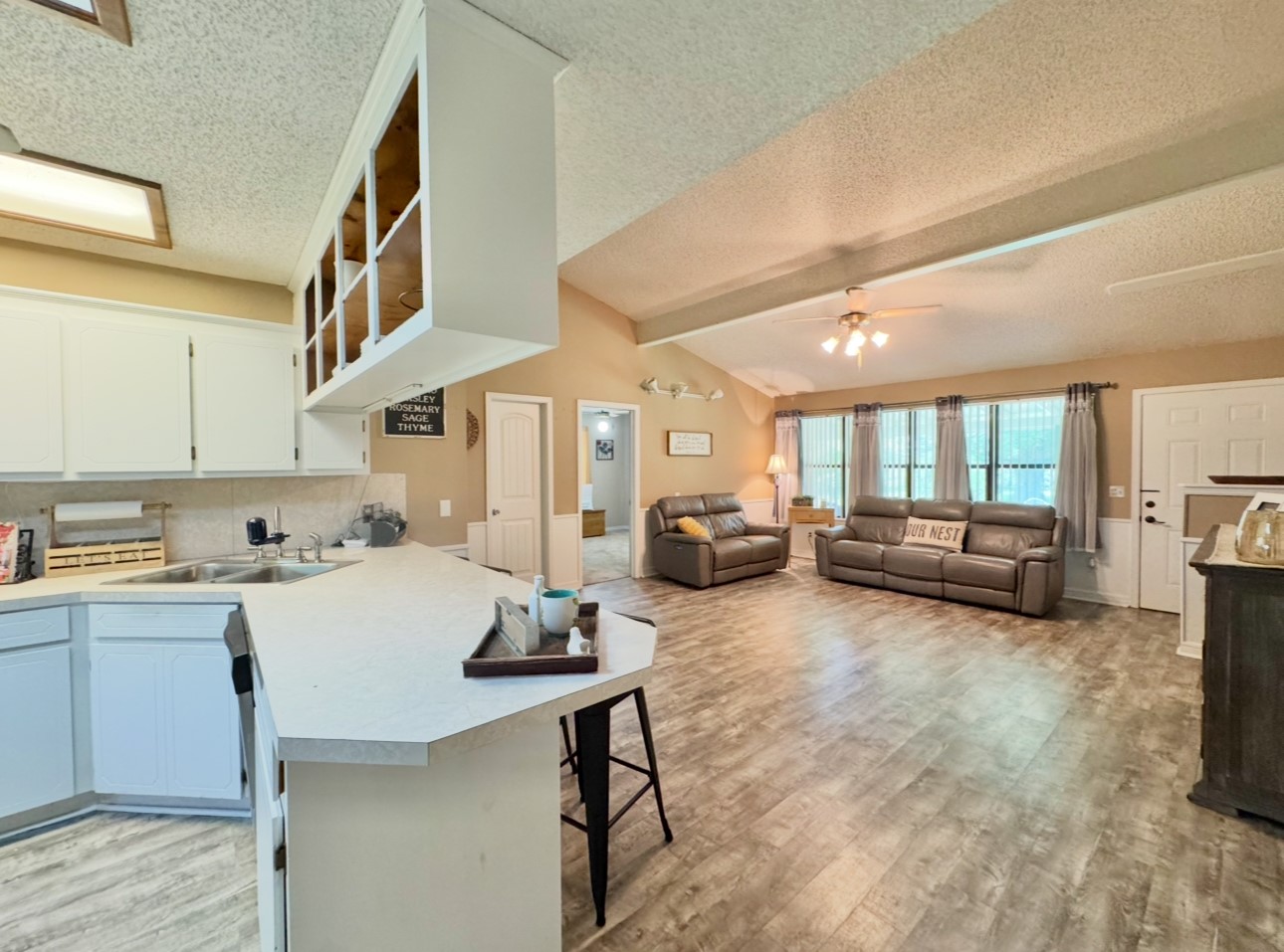 702 Pleasant Grove Road Elgin, TX 78621 - Photo 15 of 38 Kitchen featuring a textured ceiling, ceiling fan, a breakfast bar area, light countertops, and light wood-type flooring