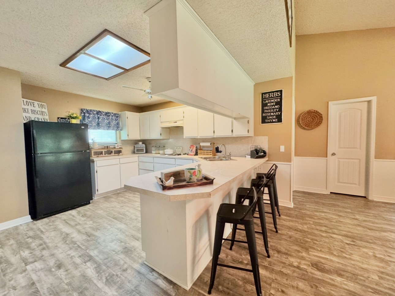702 Pleasant Grove Road Elgin, TX 78621 - Photo 17 of 38 Kitchen featuring freestanding refrigerator, a peninsula, light wood-style floors, light countertops, and a textured ceiling