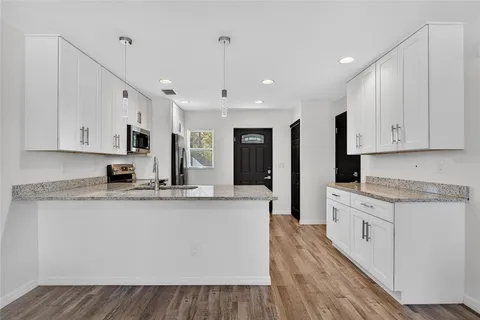 a large kitchen with stainless steel appliances granite countertop a stove a sink dishwasher and a refrigerator with wooden floor