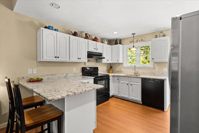 a kitchen with a refrigerator a stove a sink a dining table and chairs