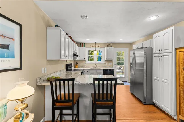 a kitchen with stainless steel appliances granite countertop a dining table chairs refrigerator and sink