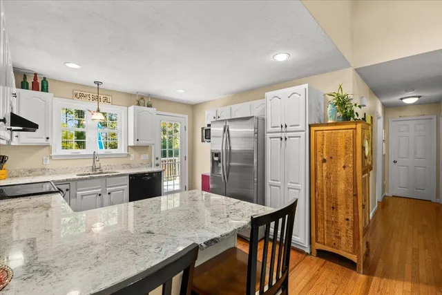 a kitchen with stainless steel appliances granite countertop a refrigerator a stove a sink a dining table and chairs with wooden floor