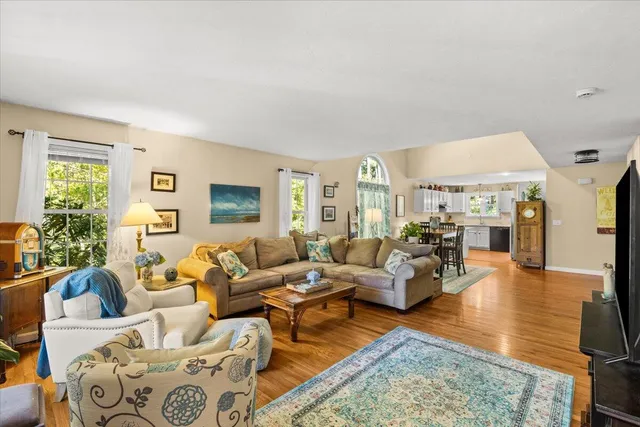 a living room with furniture large window and wooden floor