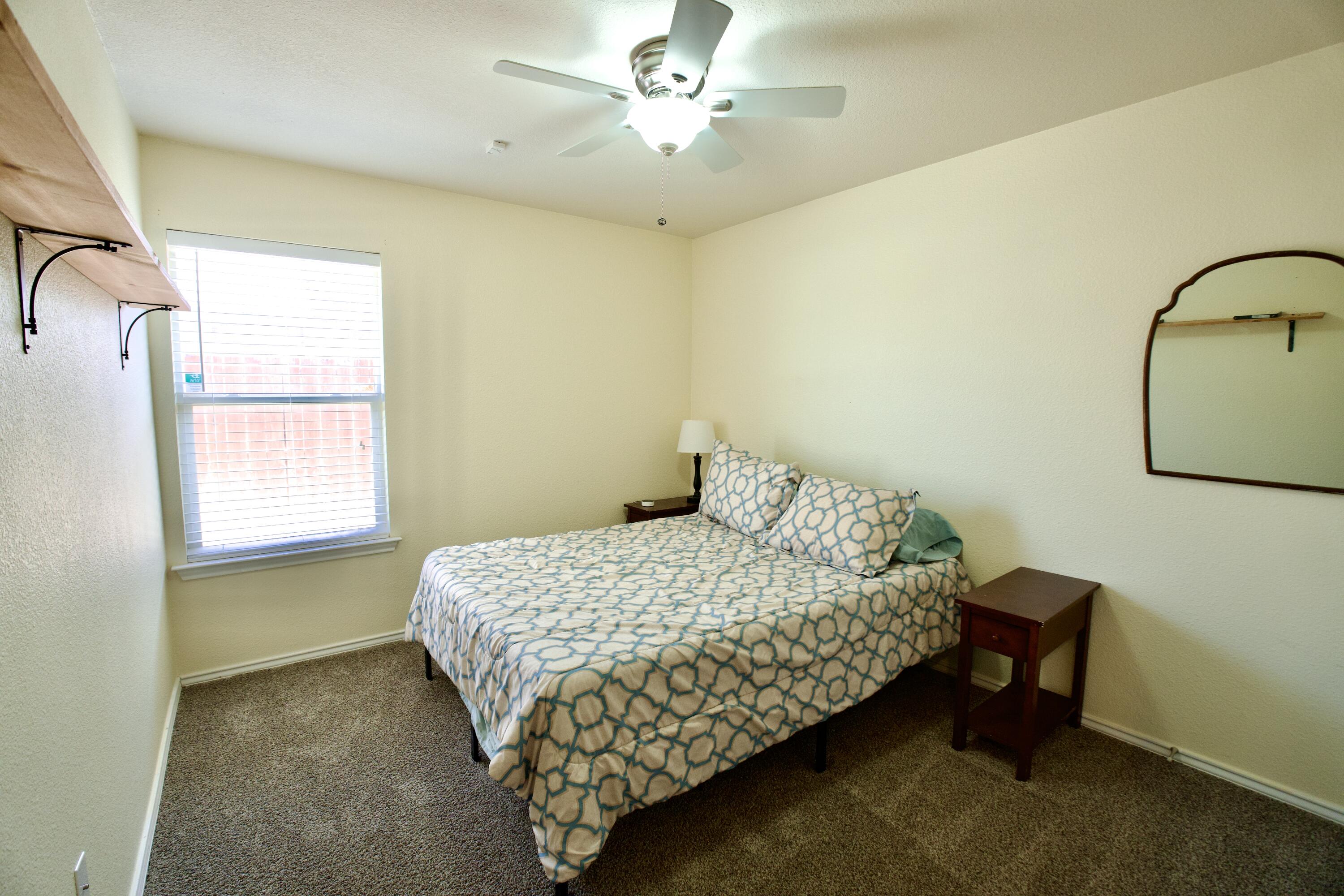 8811 16th Street Lubbock, TX 79416 - Photo 7 of 17 a bedroom with a bed chandelier and a window
