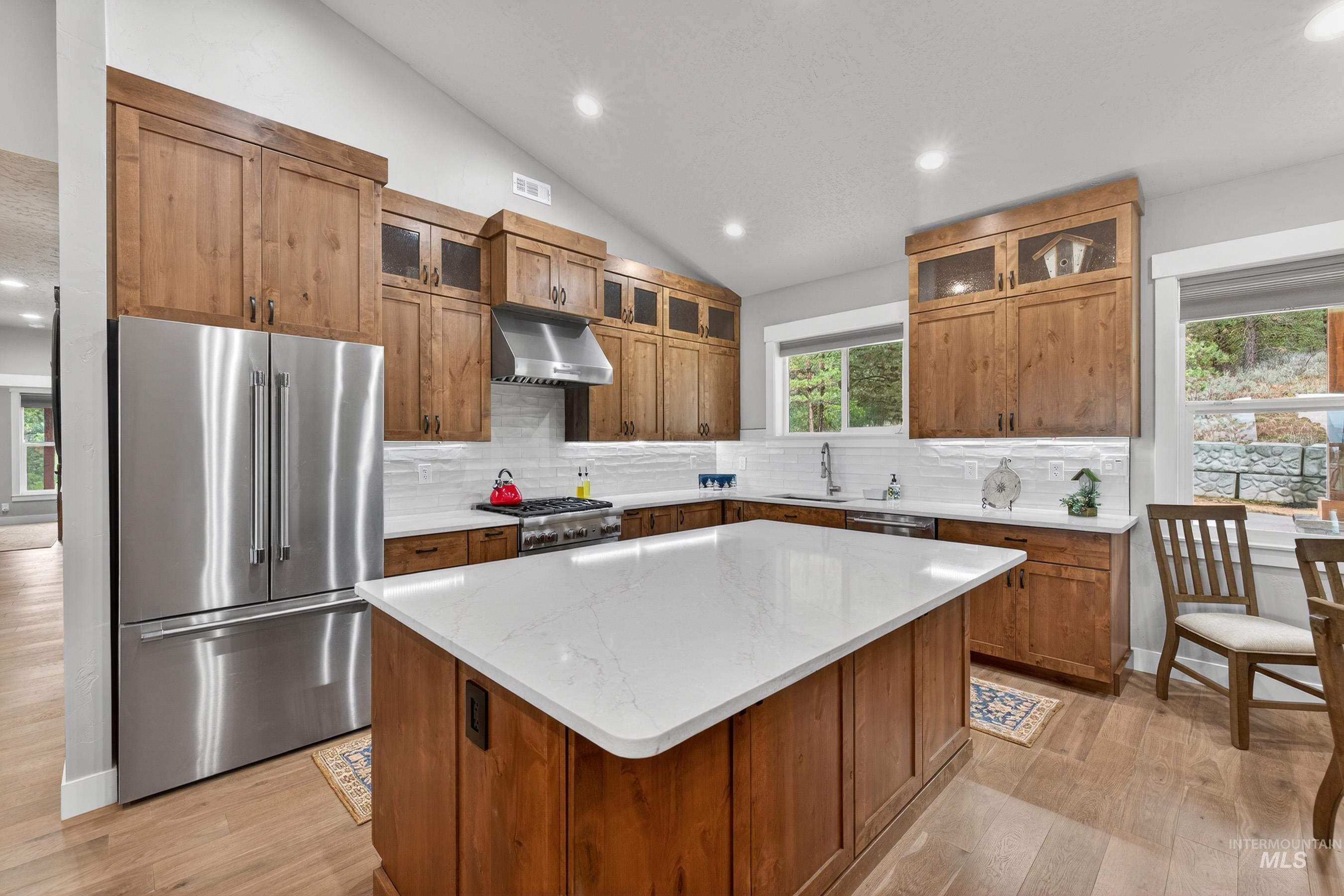 10191 Timberrim Drive Cascade, ID 83611 - Photo 14 of 44 Kitchen featuring glass insert cabinets, high end fridge, lofted ceiling, a center island, and light wood-style floors