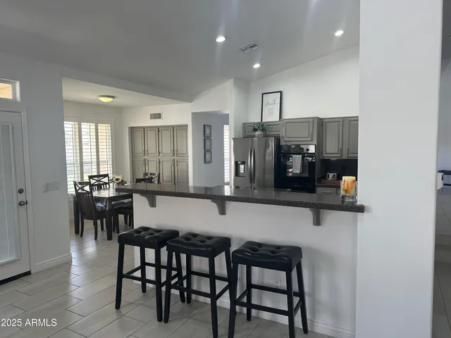 a kitchen with stainless steel appliances refrigerator dining table and chairs