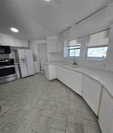 a kitchen with a sink a stove cabinets and a window