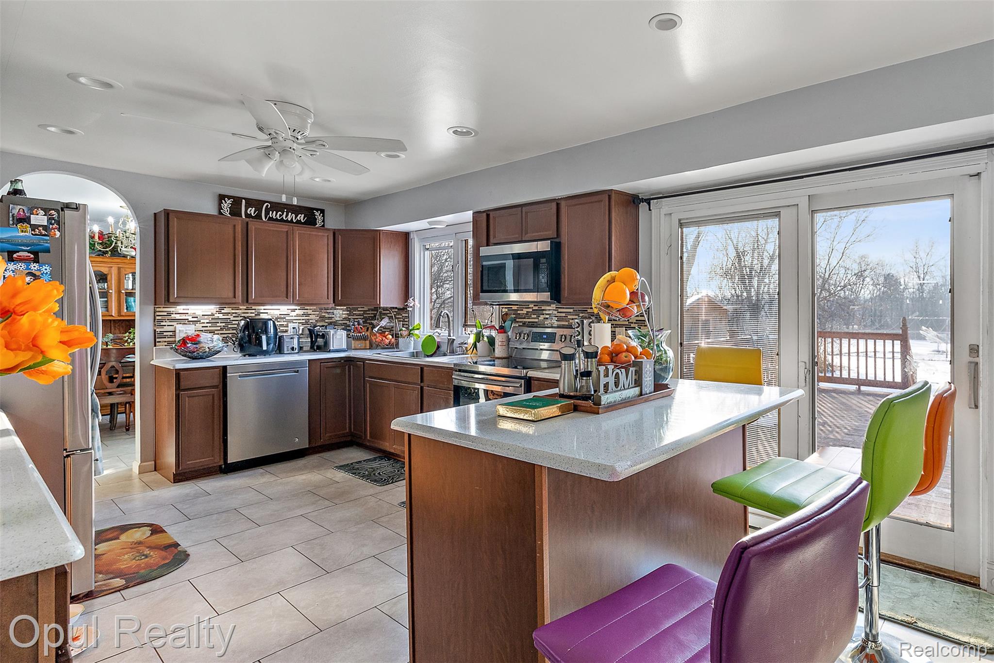 8855 Gross Road Dexter, MI 48130 - Photo 13 of 45 Kitchen featuring warm wood cabinetry, stainless steel appliances, a stone tile backsplash, light-toned countertop surfaces, and tile flooring