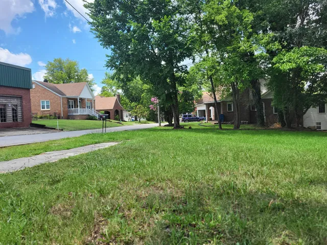 a view of a house with a big yard and large trees