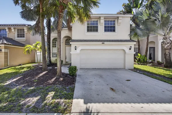 a view of a house with a yard and palm trees