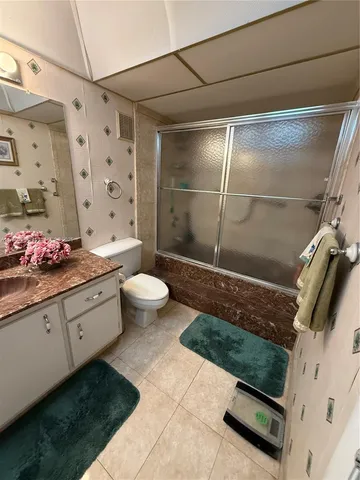 a bathroom with a granite countertop sink a toilet and shower