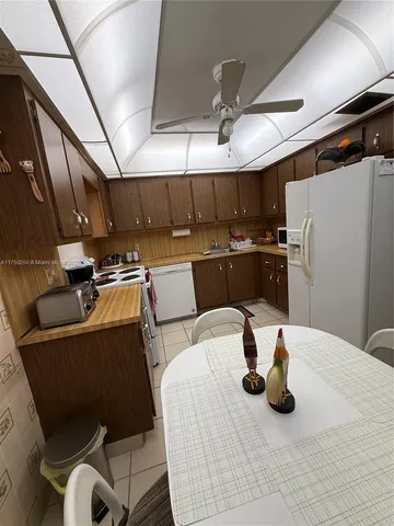 a kitchen with stainless steel appliances kitchen island granite countertop a table chairs and a refrigerator