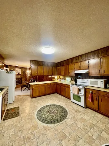 a large kitchen with stainless steel appliances kitchen island granite countertop a sink and cabinets