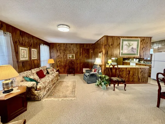 a living room with furniture kitchen view and a large window