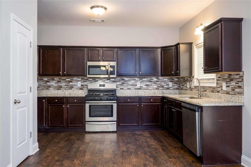 68 Crescent Commons Drive Dallas, GA 30157 - Photo 8 of 26 a kitchen with kitchen island granite countertop a stove sink and cabinets