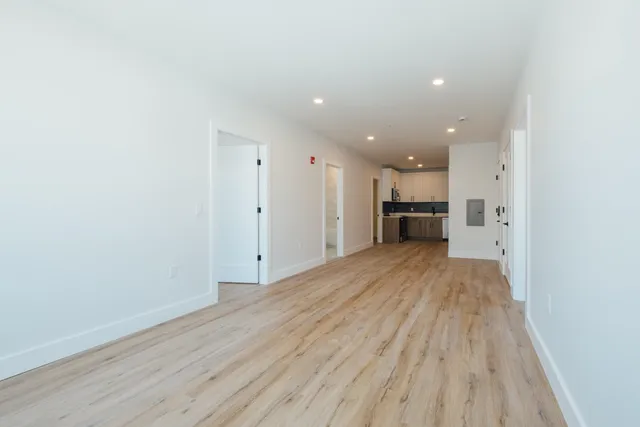 a view of empty room with wooden floor and a window