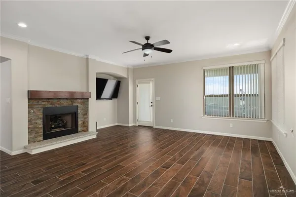 an empty room with wooden floor fireplace and windows