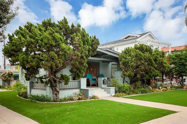 a view of a house with a yard potted plants and a large tree