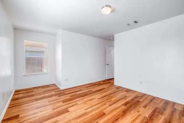 a view of empty room with wooden floor