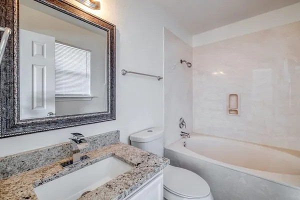 a bathroom with a granite countertop sink toilet tub and shower