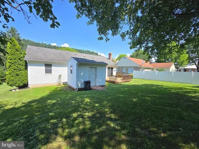 a backyard of a house with plants and large tree