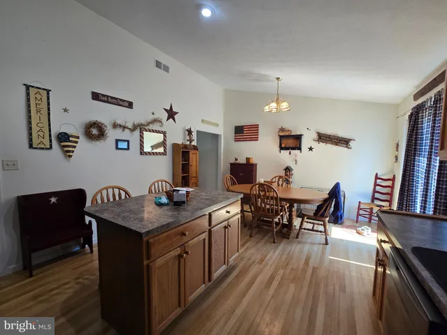 a kitchen with a kitchen island hardwood floor sink stove dining table and chairs