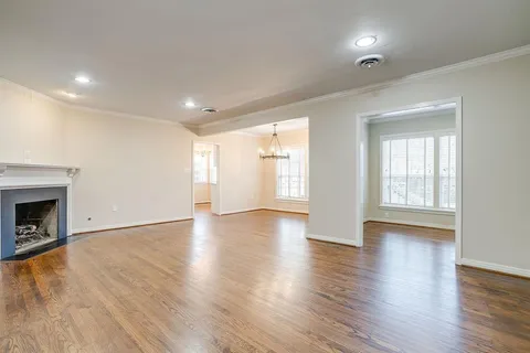 an empty room with wooden floor fireplace and windows