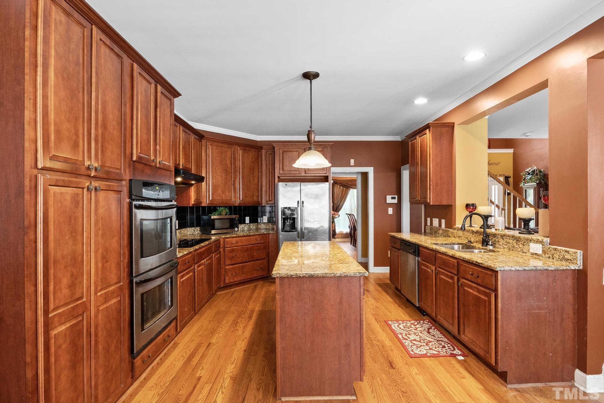 836 Crown Crossing Lane Raleigh, NC 27610 - Photo 16 of 31 a large kitchen with stainless steel appliances granite countertop a stove oven and a refrigerator with wooden floor