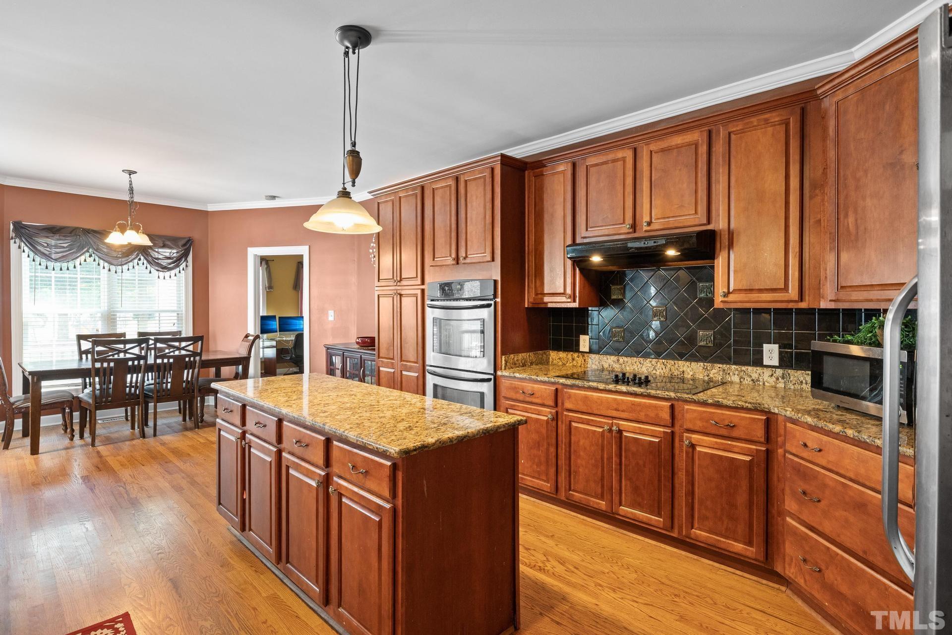 836 Crown Crossing Lane Raleigh, NC 27610 - Photo 18 of 31 a kitchen with stainless steel appliances granite countertop a refrigerator a sink dishwasher a oven and a dining table with wooden floor