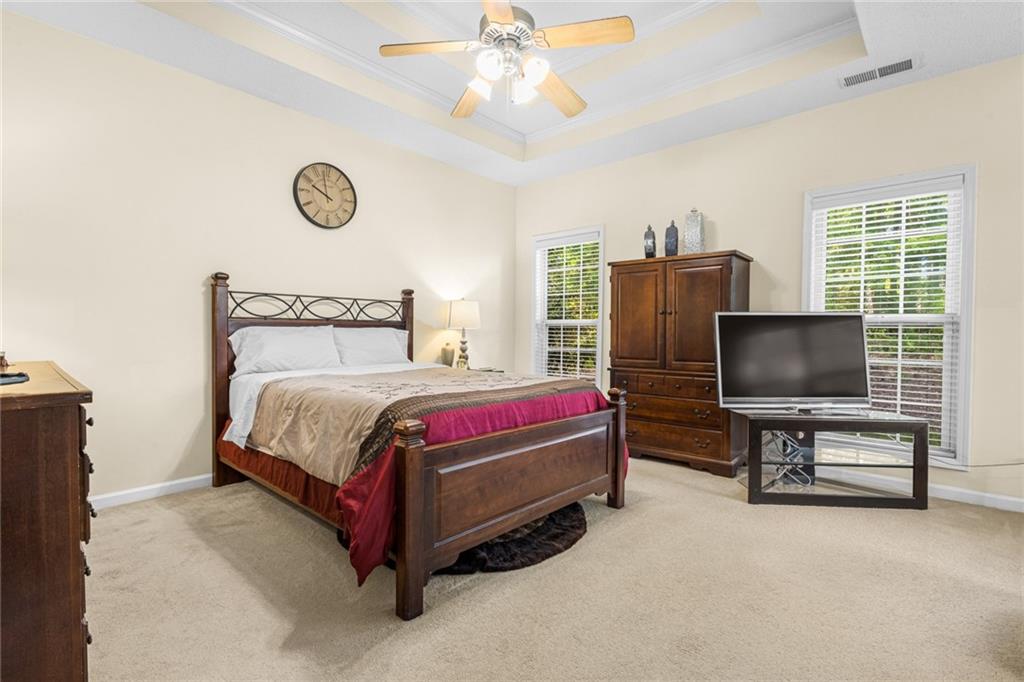 825 Lincoln Square Locust Grove, GA 30248 - Photo 15 of 29 a bedroom with a bed and a chandelier with a flat tv screen