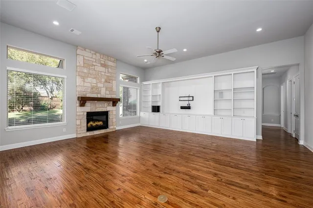 an empty room with wooden floor fireplace and windows