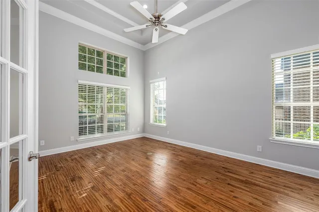 an empty room with wooden floor fan and windows