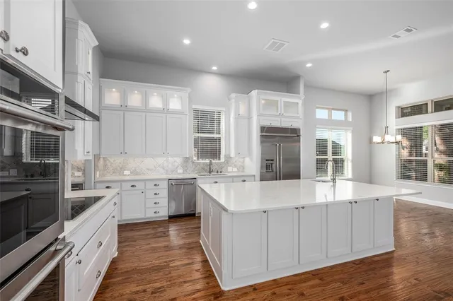 a large white kitchen with a large window and stainless steel appliances