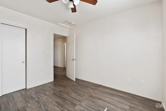an empty room with wooden floor ceiling fan and windows