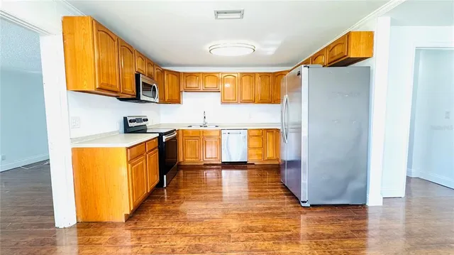 a large kitchen with stainless steel appliances granite countertop a sink and a wooden floor