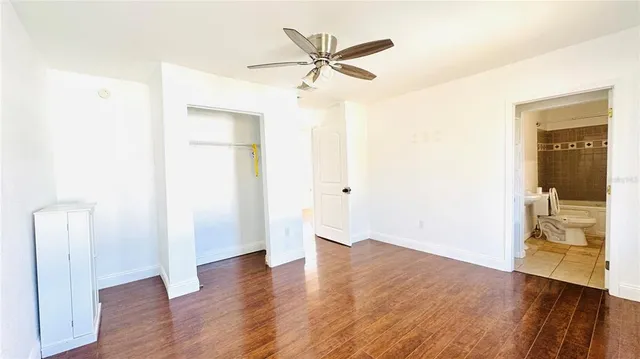 an empty room with wooden floor and a ceiling fan