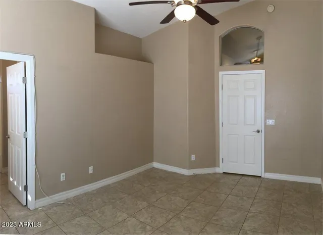 an empty room with a chandelier fan and closet