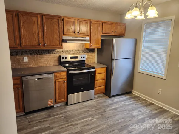 a kitchen with kitchen island granite countertop wooden cabinets and stainless steel appliances