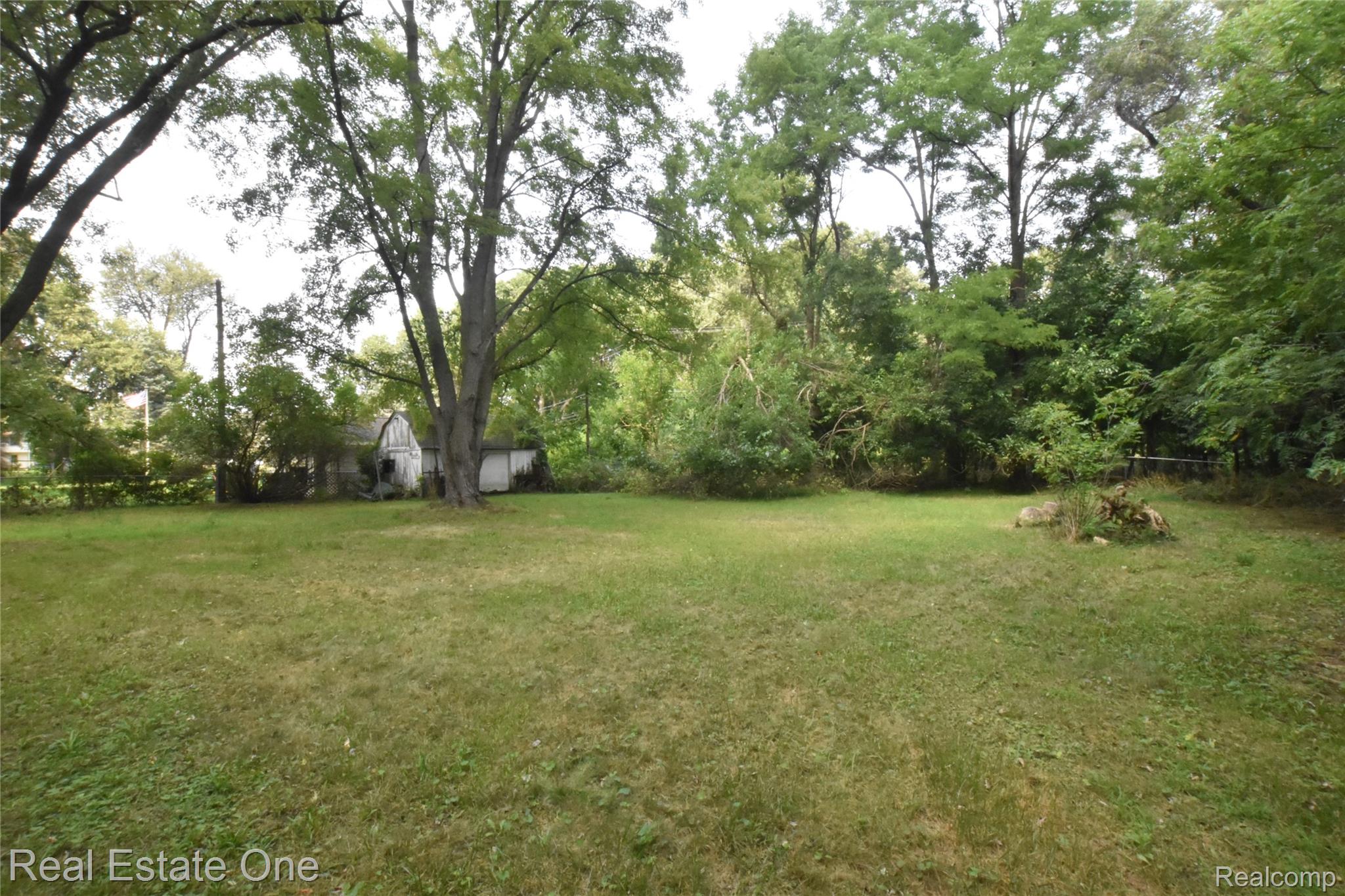 3482 West Maple Road Wixom, MI 48393 - Photo 4 of 17 Expansive grassy area with mature trees and dense perimeter foliage