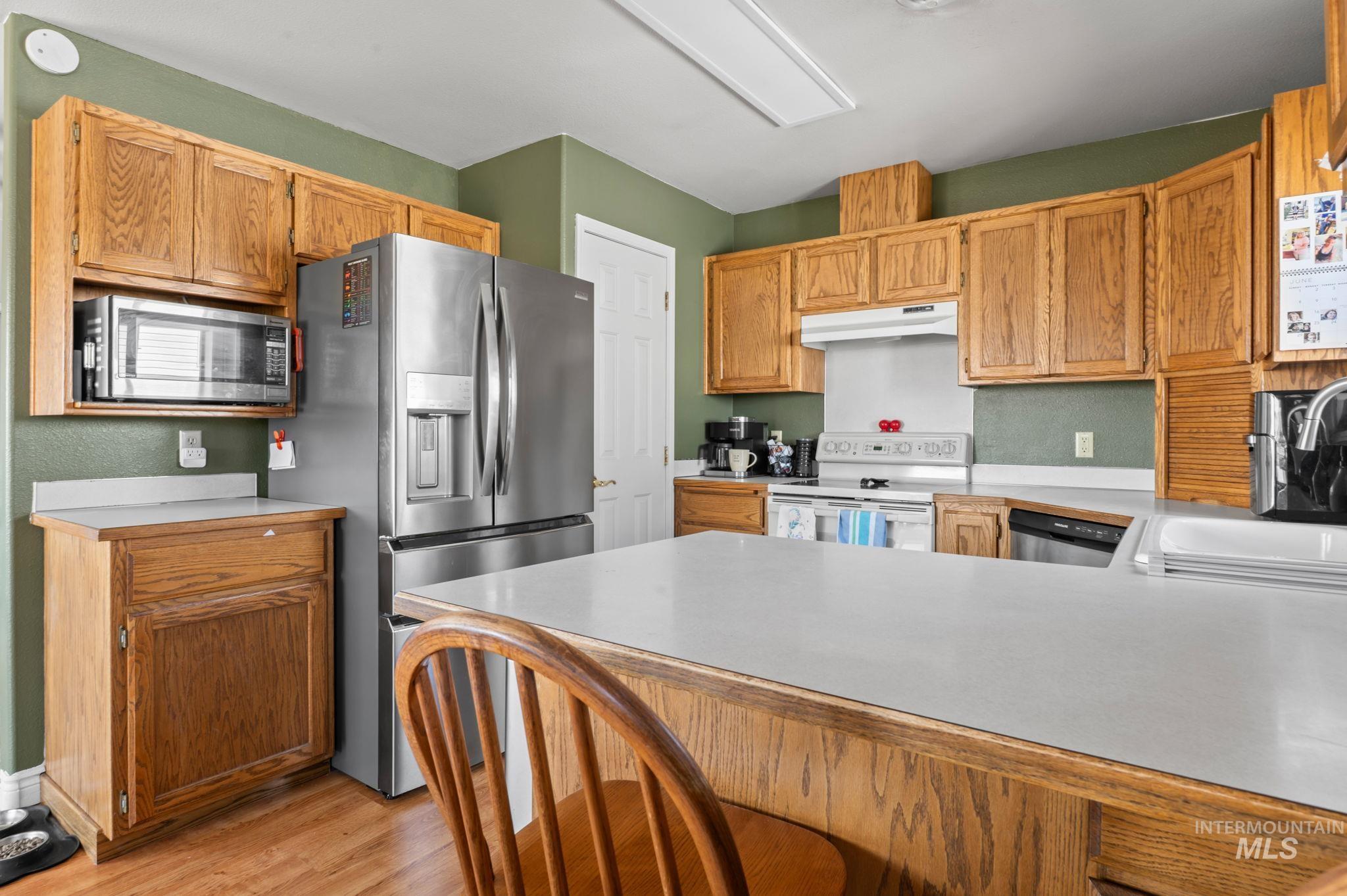 1443 29th Street Lewiston, ID 83501 - Photo 5 of 26 Kitchen with stainless steel appliances, under cabinet range hood, a peninsula, light wood-style flooring, and light countertops
