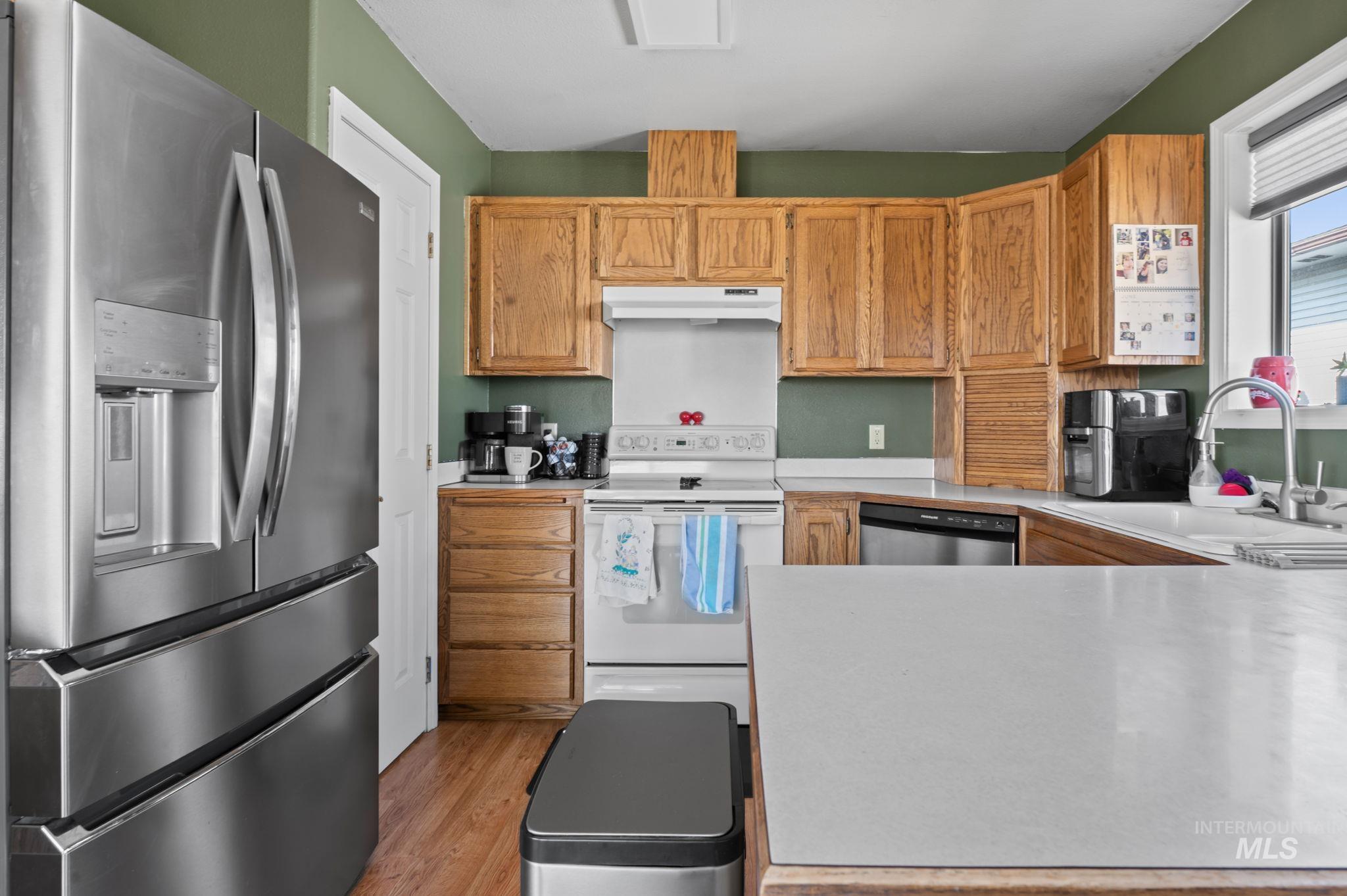 1443 29th Street Lewiston, ID 83501 - Photo 6 of 26 Kitchen with stainless steel appliances, under cabinet range hood, light countertops, and light wood-style floors