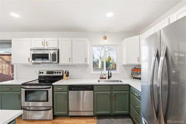 a kitchen with stainless steel appliances a sink a stove a microwave a refrigerator a stove and cabinets