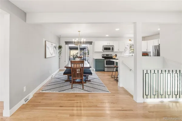 a dining room with wooden floor and kitchen view