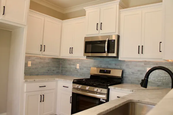 a large kitchen with stainless steel appliances a large counter top a stove a sink and a refrigerator