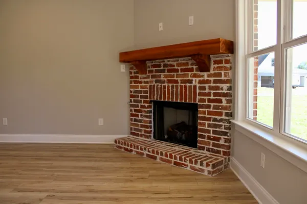 a view of an empty room with wooden floor and a fireplace
