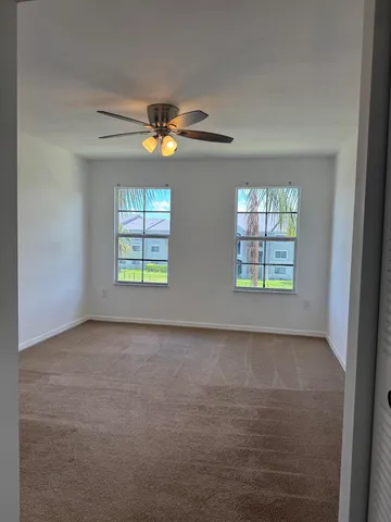 an empty room with windows and chandelier fan