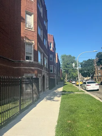 a view of a brick house with a yard and plants
