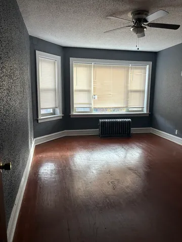a view of an empty room with a window and wooden floor