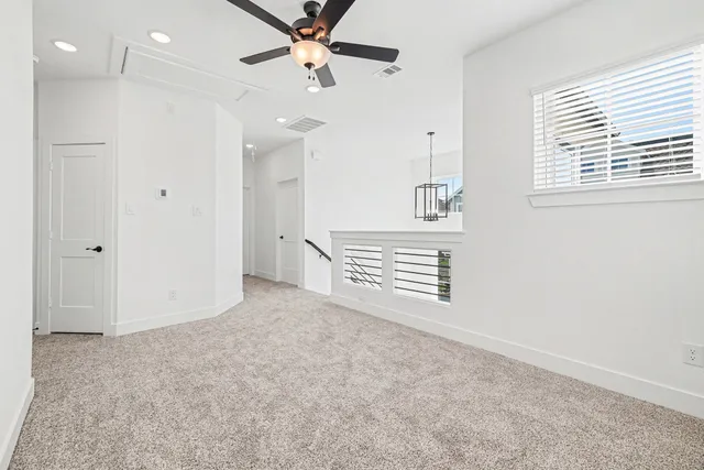 an empty room with windows and ceiling fan