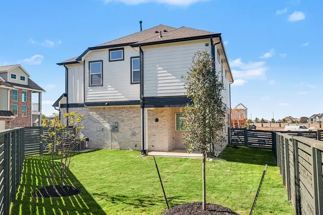 a front view of a house with a yard and a large tree